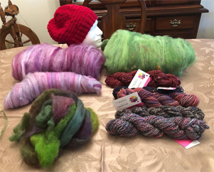 In the photo above are fiber batts I have created as well as finished yarn from handmade fiber batts. The romney roving in the front was dyed with leftover Easter egg dye. The hand knit red hat in the back is made with handspun blue faced leicester and wensleydale fiber.