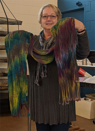 On the left Ellen is holding the painted warp shawl she wove (it took a long warping process to distribute the warp colors as you see them). On the right is a close up of her highly textured scarf, woven with 24 epi tencel warp and colcolastic weft in a twill.