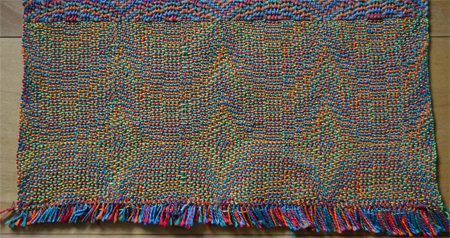 From Margie: These did not photograph very well for me, so I am sending the couple of them that were okay. The patterns, which are readily visible when you are looking at them firsthand, do not show up well through the camera lens. The Jin patterns just were not visible at all through the lens. I left the edging on the one with yellow weft to show the color of the warp (green, red, orange and blue) which was the same for both pix, and the effect of the weft on that color. They are both Chakras patterns in Echo. Great class with lots of added tips and tricks!