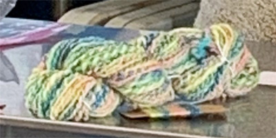 Sharon was challenged to fractal spin a multicolor hand-dyed braid, worsted weight. She divided the braid of roving into lengthwise sections of different thicknesses, spun the sections individually, and then plied them together to create her lovely yarn. Fractal spinning made the color changes more gradual and subtle along the length of her yarn compared to the color changes that would have resulted had she used a simpler spinning technique.