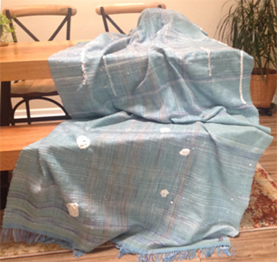 From Jeanne D.:This is a throw made on my loom of wool, alpaca and tencel. It's a "Frozen" topped with "icicles" and snowballs. There are glitter discs making the snow. 43" by 88" long minus the fringe.