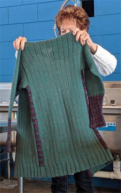 Using green wool for the body of this duster coat cardigan, Jeanne then added red wool/alpaca yarn in the trim areas.