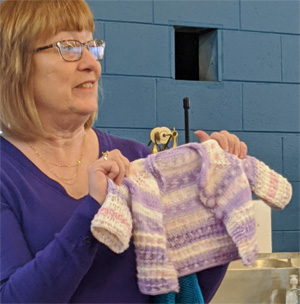 Sue knit yet another baby sweater for the next member of her extended family.